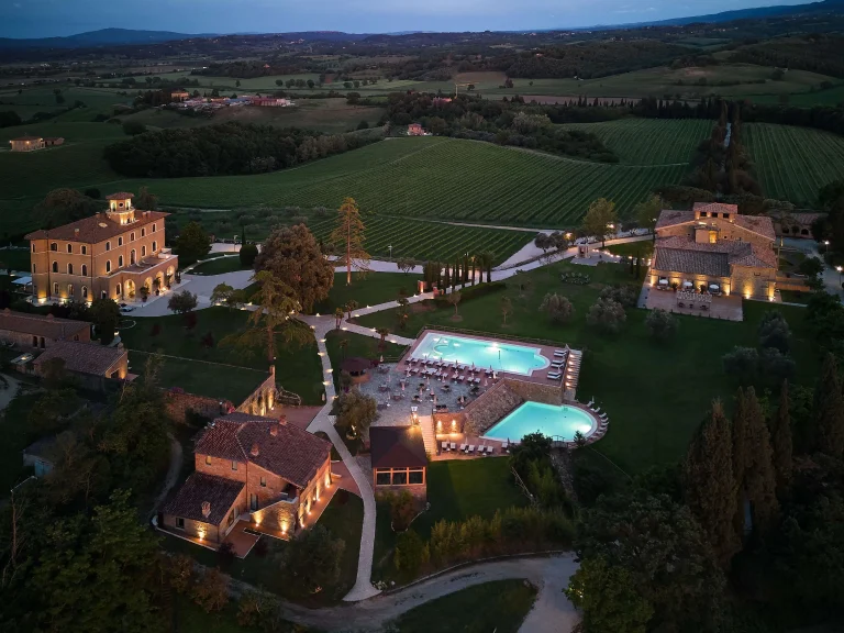 Aerial view of Precise Tale Poggio Alla Sala surrounded by the rolling hills, vineyards, and countryside of Tuscany.