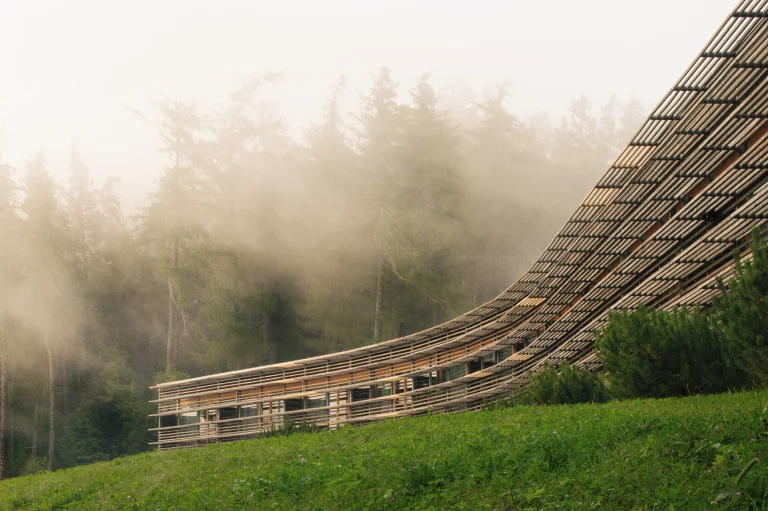 Vigilius Mountain Resort exterior by Matteo Thun, grass-covered roof merging with the alpine slope in South Tyrol