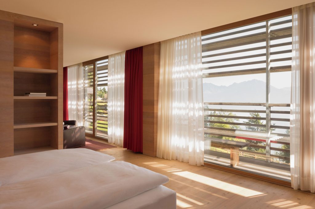 Floor-to-ceiling window in a Vigilius Mountain Resort room framing the Dolomite mountains in South Tyrol