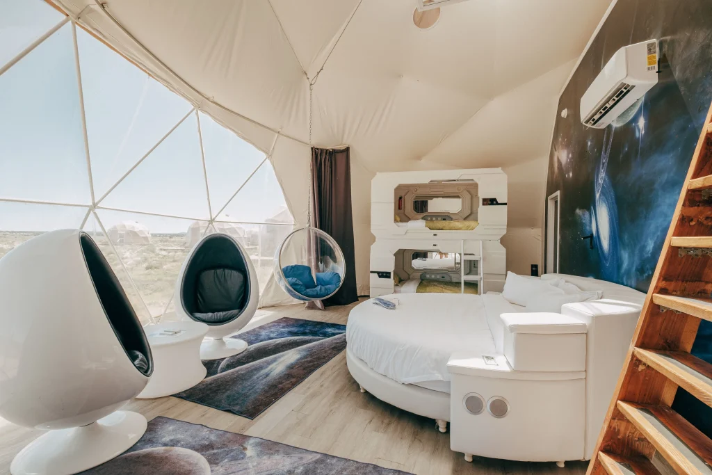 Interior of a glass dome hotel room at Grand Canyon with bed facing transparent dome ceiling and star-filled night sky