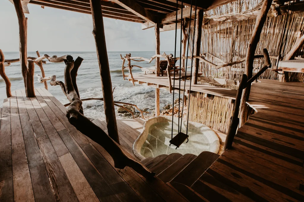 Azulik Tulum outdoor stone bathtub open to jungle canopy and Caribbean sky, surrounded by natural wood and thatched materials