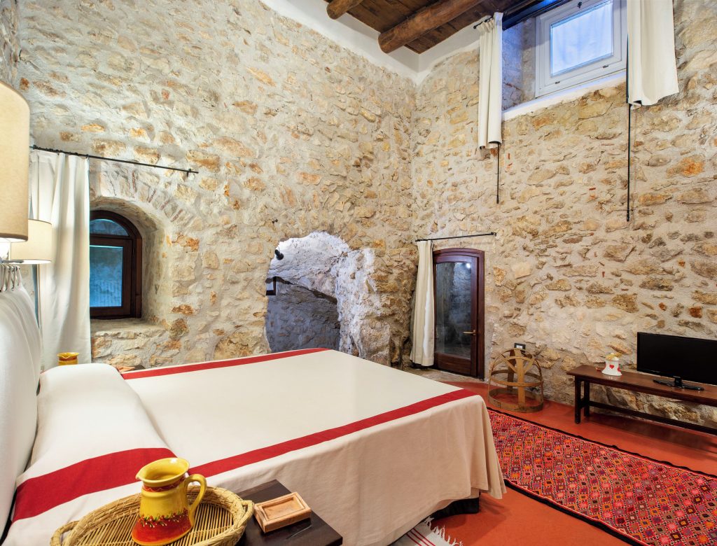 Restored bedroom interior at L'Armoniosa inside Macchiaroli Castle, stone walls and elegant furnishings