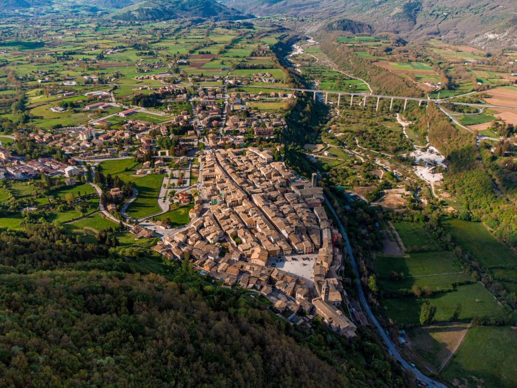 Aerial view of a picturesque Italian town surrounded by lush fields and hills.